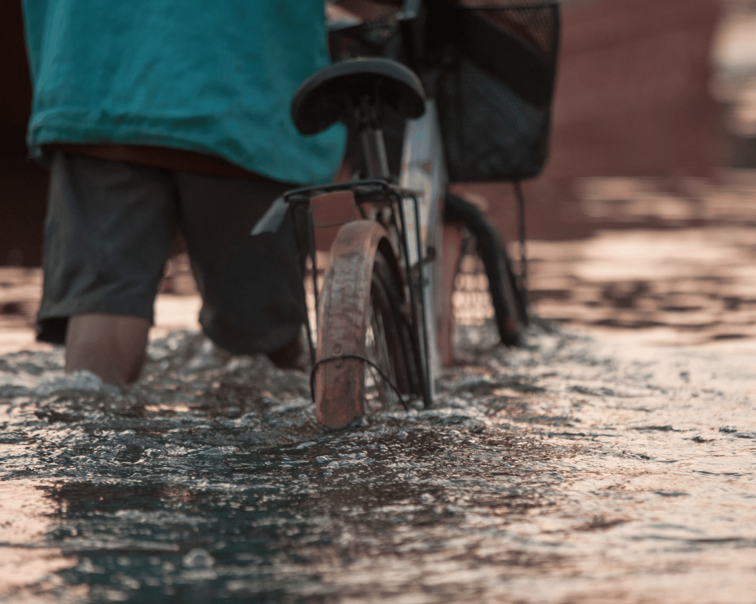 Mann schiebt sein Fahrrad durch Hochwasser. Symbolbild für den Klimawandel, auf den sich ESRS E1 fokussiert