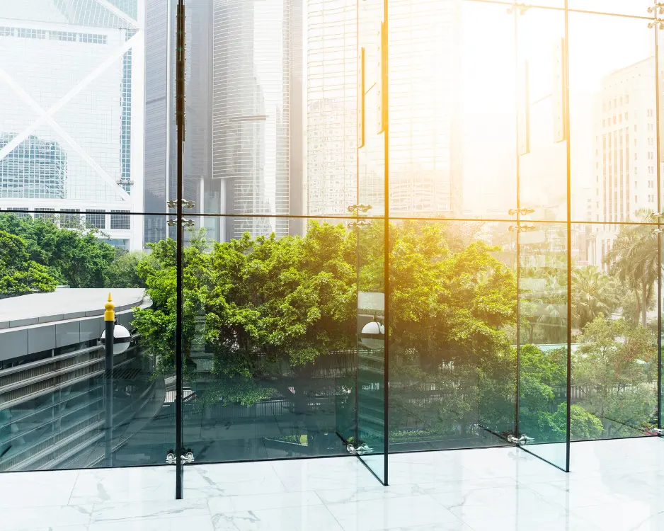 Moderne Glasfassade mit Blick auf Grünflächen und Hochhäuser als Sinnbild für nachhaltiges Bauen bei Krämmel