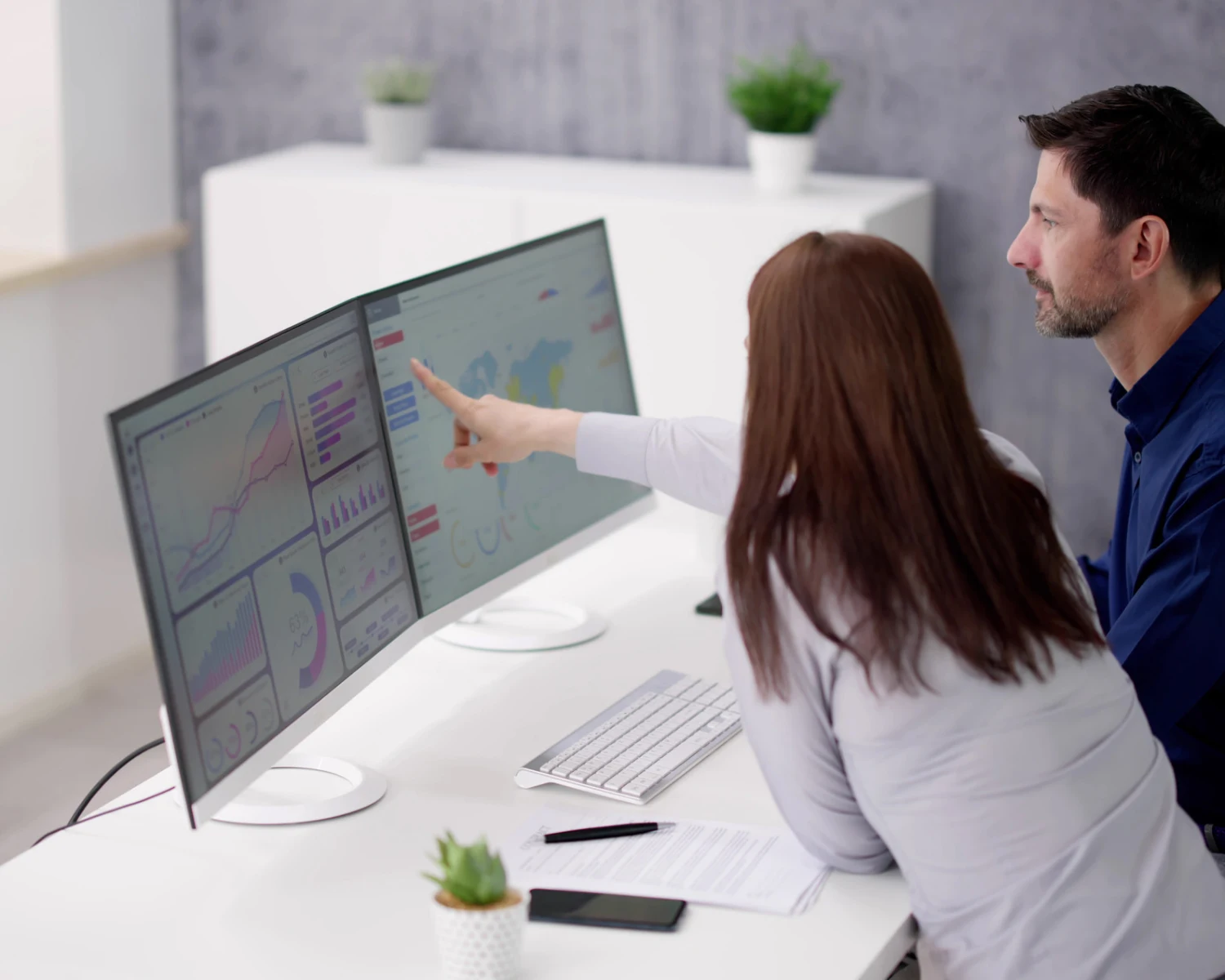 Zwei Kolleginnen und Kollegen im Büro besprechen am Dashboard-Monitor PPWR-, PCF- und DPP-Daten